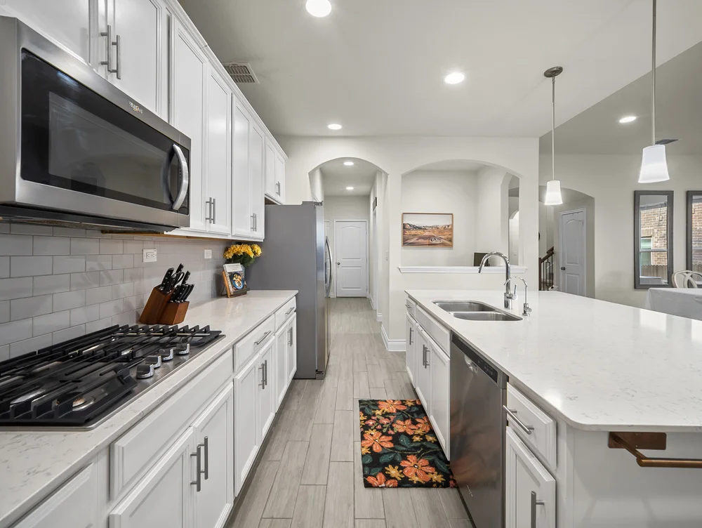 Kitchen with white cabinets, gas range and a large island with a double sink